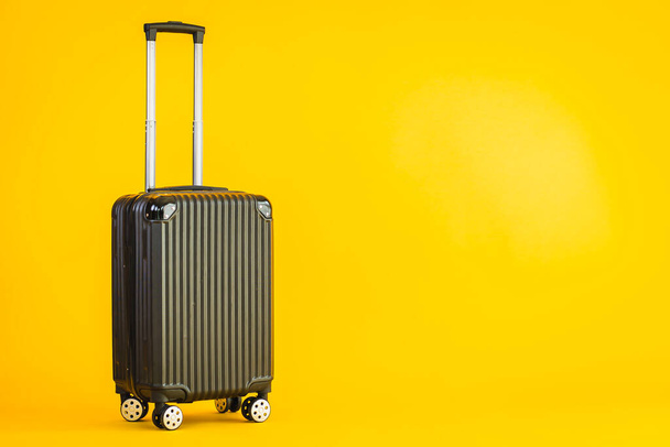 Black color luggage or baggage bag use for transportation travel and leisure on yellow isolated background - Foto, imagen