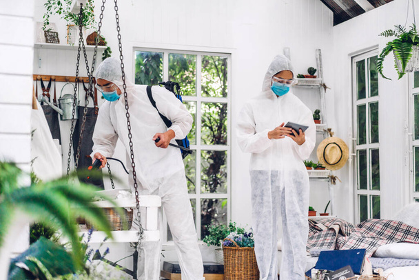 Professzionális csapatok fertőtlenítő dolgozó védő maszk és fehér ruha fertőtlenítő spray tisztító vírus, hogy segítse a szolgáltatás ölni coronavirus az ügyfél otthonában - Fotó, kép