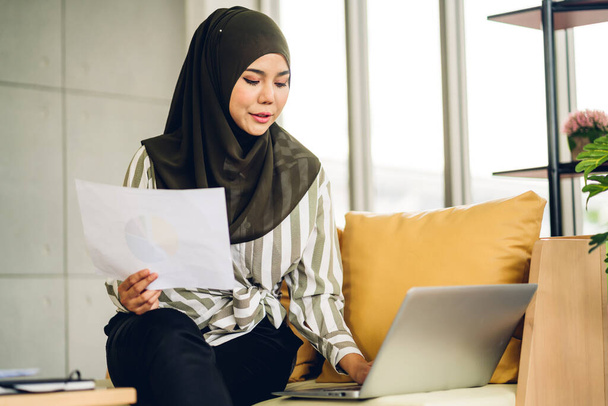 Νεαρή χαμογελαστή όμορφη μουσουλμάνα γυναίκα χαλάρωση χρησιμοποιώντας φορητό υπολογιστή εργασίας και τηλεδιάσκεψης συνάντηση στο σπίτι.. εργασία από το σπίτι έννοια - Φωτογραφία, εικόνα