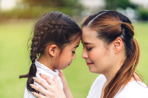 Mutlu bir aşk portresi. Asyalı bir anne ve küçük Asyalı bir kız çocuk gülümsüyor ve tatlı bir kızla yüz yüze eğleniyor. - Fotoğraf, Görsel