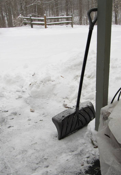 Прислонившаяся лопата на подъездной дорожке после снежной бури в зимний день в Новой Англии в Америке - Фото, изображение