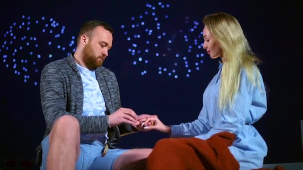 Happy man proposes wedding woman with fireworks in sky and puts ring on finger. - Video