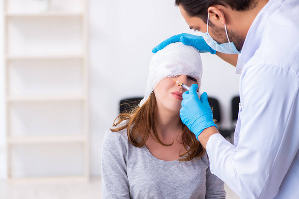 Jeune femme blessée à la tête visitant un jeune médecin masculin
 - Photo, image