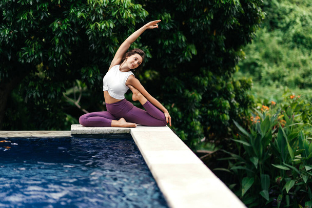 Woman practicing yoga performing yoga-asanas outdoors. - Foto, immagini