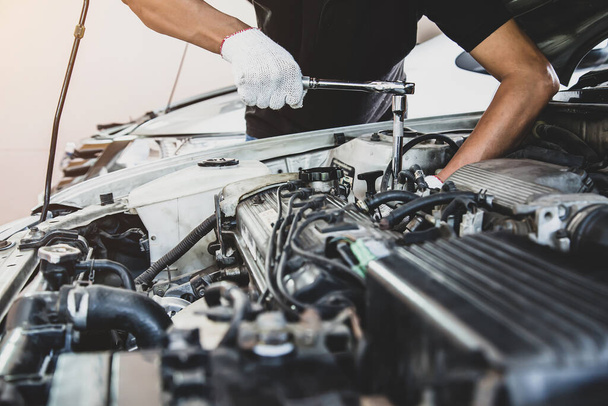 Close-up Hand des Automechanikers mit Schraubenschlüssel, um einen Automotor zu reparieren. Konzepte der Autopflege beheben Reparaturservice und Versicherung. - Foto, Bild