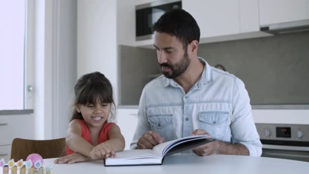 Isä auttaa pientä tytärtä oppimaan lukemaan - Materiaali, video