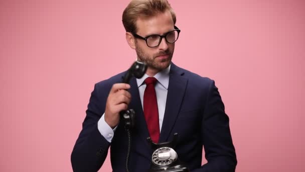 happy elegant man answering old rotary telephone, getting bad news, making an upset face, nodding and disapproving on pink background - Footage, Video