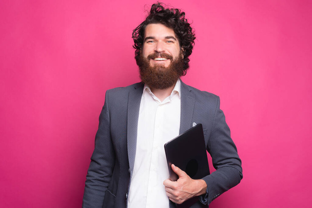 Portrait of cheerful bearded hipster man in casual holding laptop. - Photo, Image