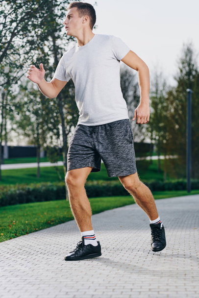 sportman in sneakers short en een t-shirt hardlopen in het park outdoor fitness - Foto, afbeelding