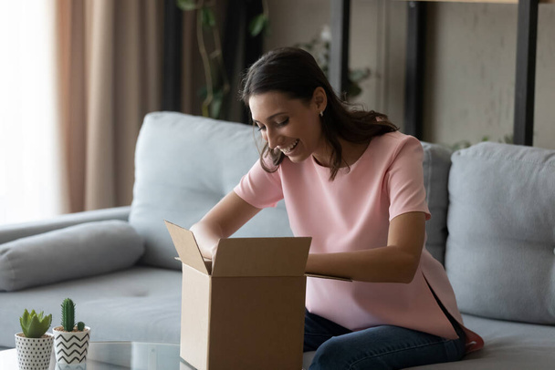 Smiling ethnic woman unpack postal package shopping online - Foto, immagini