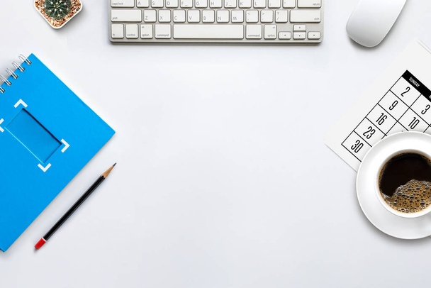 Draufsicht auf den Schreibtisch-Arbeitsplatz mit Kaffeetasse, Tastatur und Arbeitsplan auf weißem Tischhintergrund. flache Lage - Foto, Bild