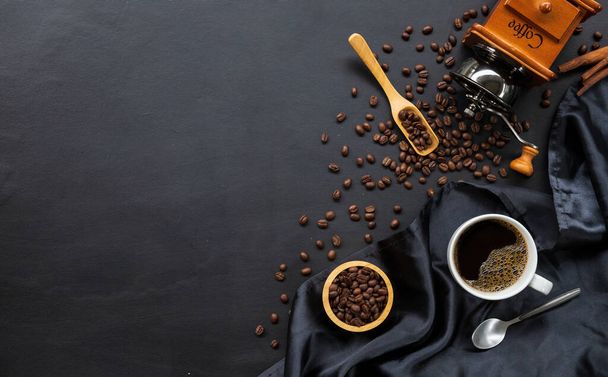 hete koffie en bonen op zwarte houten tafelondergrond. bovenaanzicht - Foto, afbeelding