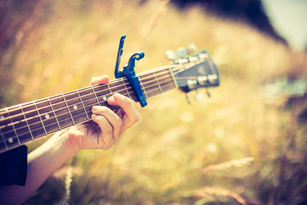 Close up of western guitar played outdoors at a river, summertime - Foto, afbeelding