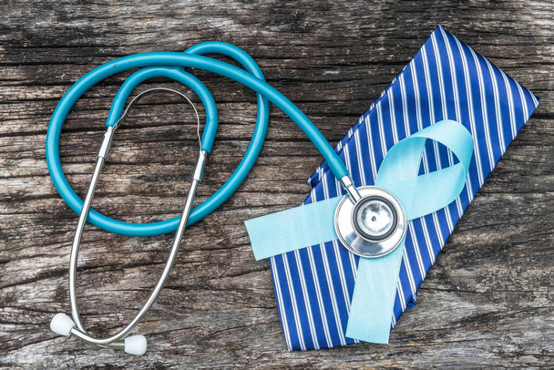 Prostaatkanker blauw bewustzijn lint voor mannen gezondheid concept met licht blauwe strik kleur op medische ziektekostenverzekering aanvraagformulier en stethoscoop op arts bureau achtergrond - Foto, afbeelding