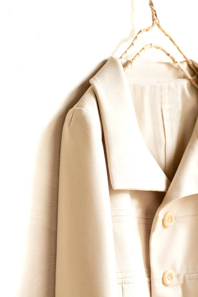 beige or white jacket hanging on clothes hanger on white background.close up. - Fotografie, Obrázek