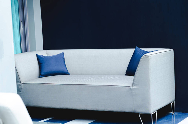 Un sofá gris para sentarse y relajarse con almohadas azules. - Foto, Imagen