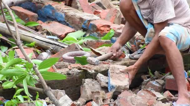 Индийский рабочий снимает старую штукатурку с кирпича и восстанавливает ее для повторного использования. - Кадры, видео
