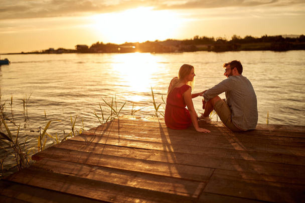 Young couple enjoying intimate moments and the sunset on the lake - Photo, image