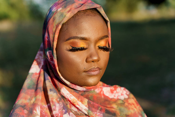 Afro-Afrikaanse zwarte vrouw in sjaal met de naam hijab. Traditionele Afrikaanse kleding. Portret van moslim vrouw met gesloten ogen. Afrikaanse nationaliteit. - Foto, afbeelding