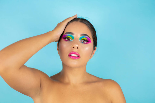 Beauty portret van vrouwelijke model met levendige make-up op blauwe achtergrond. - Foto, afbeelding