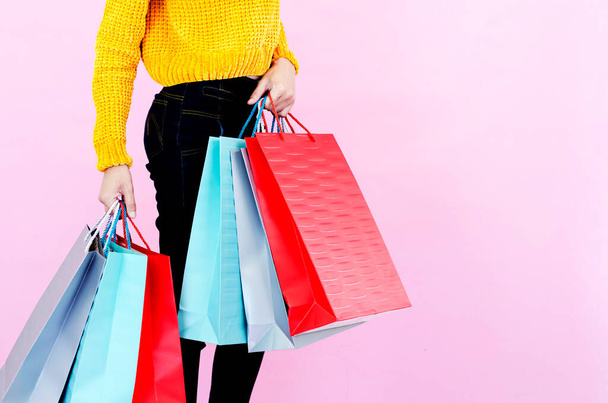 Las mujeres asiáticas usan ropa negra. Llevar una bolsa de compras en verde, gris, rojo Con fondo rosa - Foto, imagen