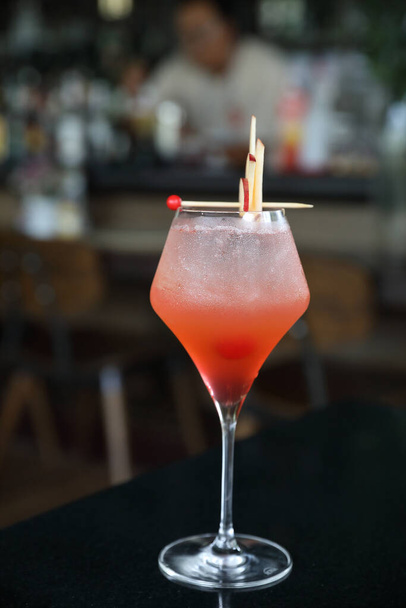 Copa de cóctel rosa con hielo en un mostrador de bar - Foto, imagen