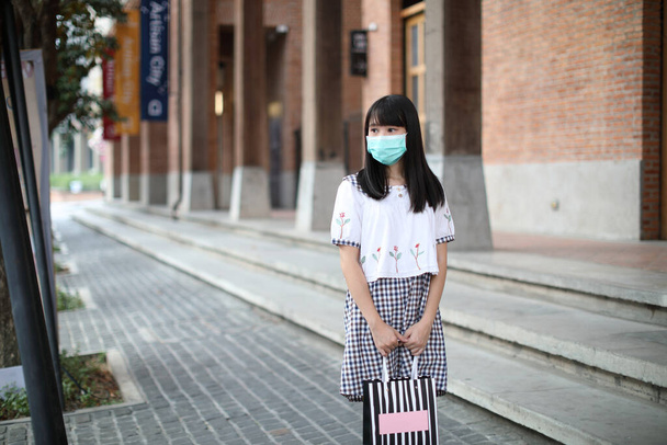 Retrato jovem mulher com máscara de compras no shopping comunitário em urbano em covid-19 surto de vírus  - Foto, Imagem