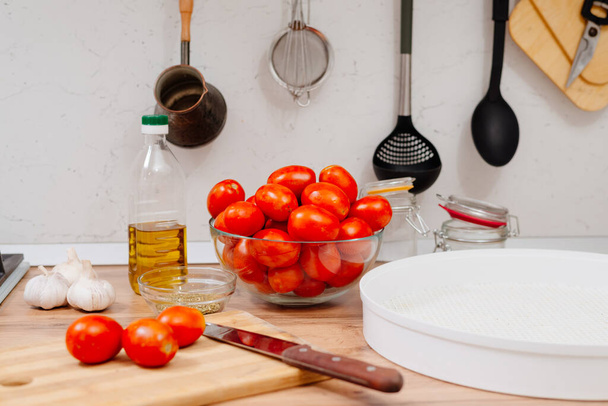 Сушені помідори. Процес приготування сушених томатів. Жінка готує помідори на кухні. Жінка розрізає помідори, змащує їх олією та спеціями
.  - Фото, зображення