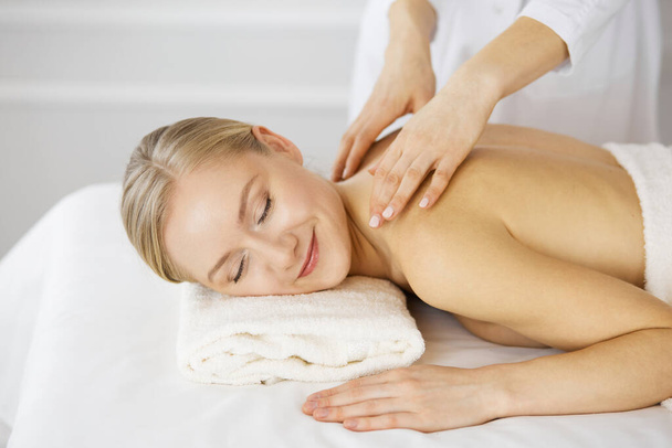 Beautiful caucasian woman enjoying back massage with closed eyes. Beauty and Spa salon concept - 写真・画像