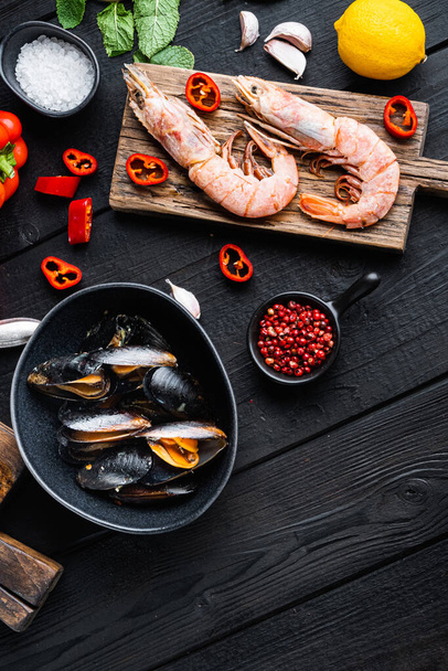 Spanische Paella-Zutaten mit Reis, Garnelen, Tintenfisch und Muschel auf schwarzem Holztisch, Draufsicht, Food-Foto. - Foto, Bild