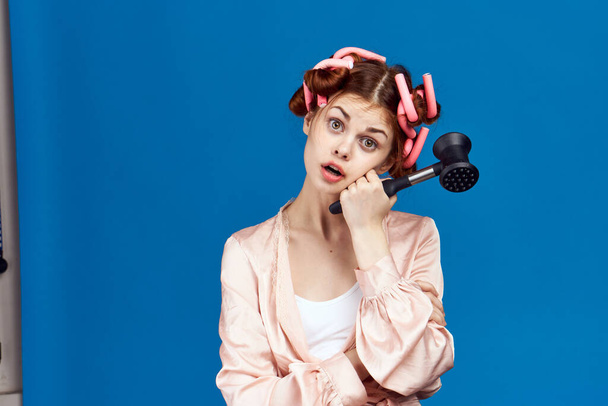 Woman with curlers on her head pink robe hammer for beating meat housewife blue background - Foto, immagini