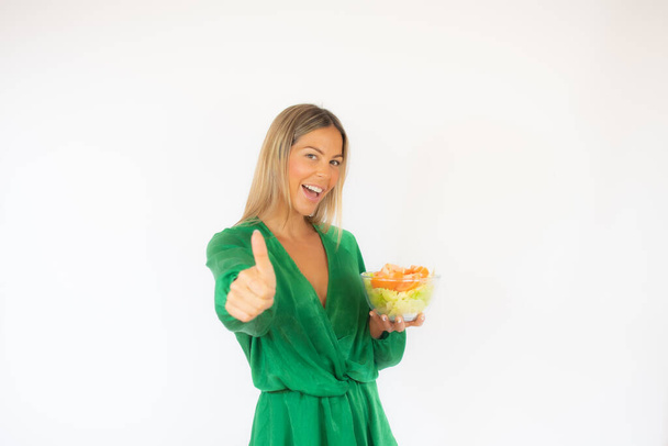 Bella donna in abito verde con un'insalata sorridente - Foto, immagini