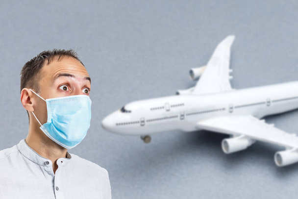 man in a protective mask on the background of the plane. Protection against Coronavirus and gripp - Photo, image