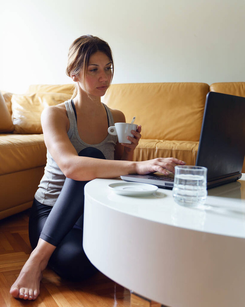 Fiatal felnőtt kaukázusi nő dolgozik a laptop számítógép otthonról ül a kanapén nap felvétel online női szabadúszó vagy vásárlás online hatékonyság és szakértelem pénzt koncepció - Fotó, kép