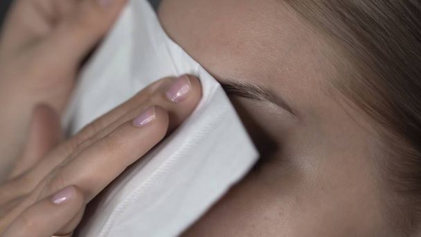 Close up of make-up artist making professional make-up for young woman in beauty studio. Makeup Artist uses paper wipe to clean models face - Fotó, kép