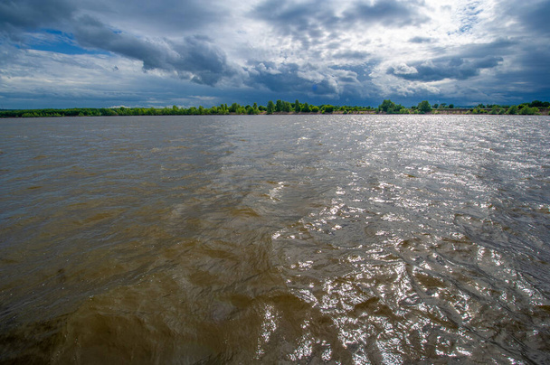 夏の写真、強力な雷雲、青い空、暗い鋭い水、観光客が多摩川沿いを歩く - 写真・画像