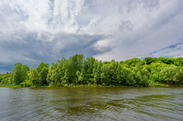 Foto, Krachtige Donderwolken, Blauwe lucht, Donker scherp water, Toeristische wandeling langs de Kama Rivier - Foto, afbeelding
