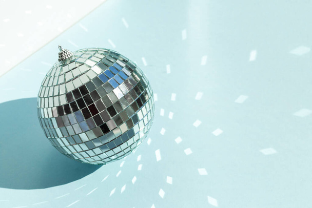 Shining disco ball on blue background. Disco ball with bright rays - Image - Zdjęcie, obraz