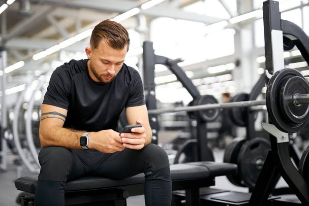 tired fitness man using smartphone in gym - Фото, зображення