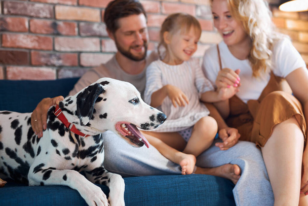 retrato de jovem família caucasiana se divertindo com o cão em casa - Foto, Imagem