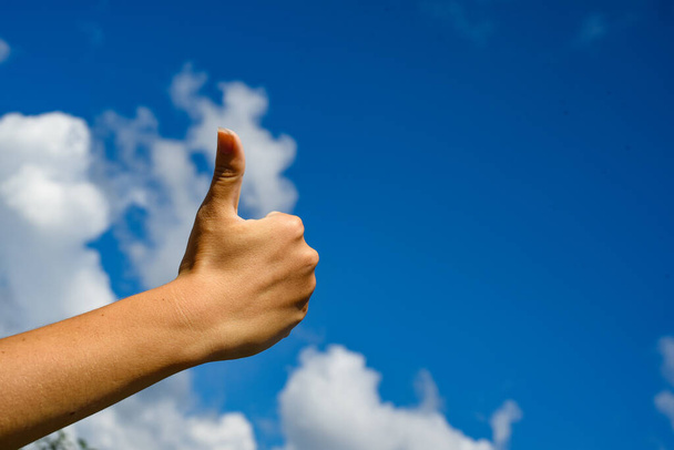Thumb up in the sky. Hand show thumbs up on a blue sky - Foto, afbeelding