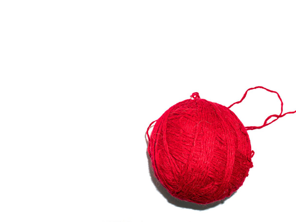A ball of thread for knitting clothes. White background. Handmade. Burgundy woolen threads for knitting. Background image. Place for your text. Textile industry. - Photo, image