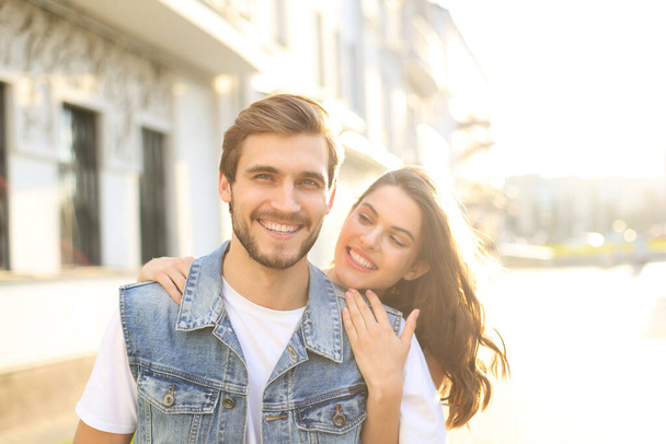 Beautiful young couple in love walking outdoors at the city street, hugging - Fotoğraf, Görsel