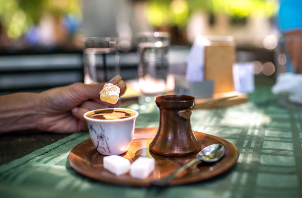 Tradycyjna turecka czarna kawa i słodki deser lokum na stole w restauracji. Korzystanie orientalne smaki z autentycznych garnków.  - Zdjęcie, obraz