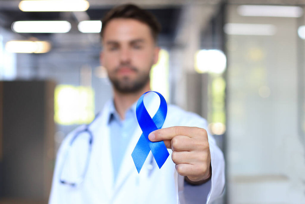 Main de médecin avec ruban bleu de sensibilisation au cancer de la prostate. Médecine oncologie gros plan ciel symbole - Photo, image