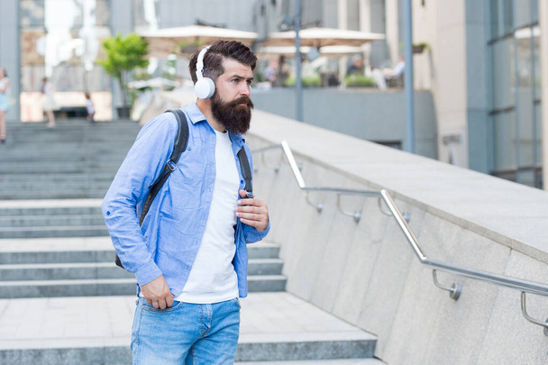 Daily route to work. Modern life. Change of scenery concept. Handsome hipster with backpack walking street. Walking through empty streets. Man with headphones walking city center. Listening music - Foto, Bild