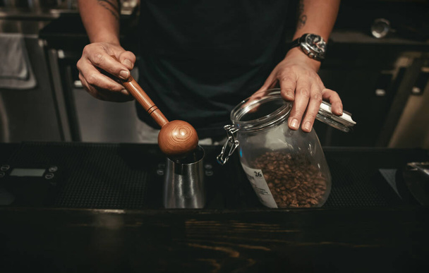 カフェでコーヒーを作るバリスタ。木製スプーンでコーヒー豆を測定 - 写真・画像
