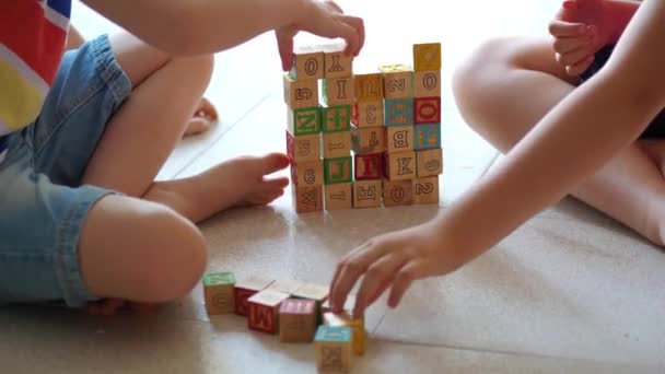 παιδιά παίζουν με τα γενικά ξύλινα τούβλα στο πάτωμα στο σπίτι - Πλάνα, βίντεο