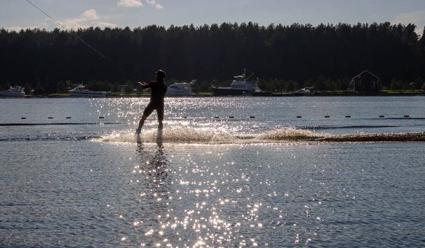 Silhouette sciatore d'acqua che si muove veloce in spruzzi d'acqua al tramonto - Foto, immagini