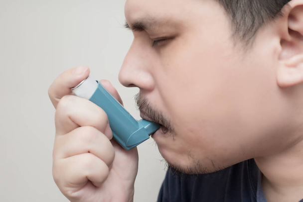 Asiatische fetthaltige Mann mit einer Druckpatrone Inhalator erweitert Pharynx, Bronchodilatator. weißer Hintergrund - Foto, Bild